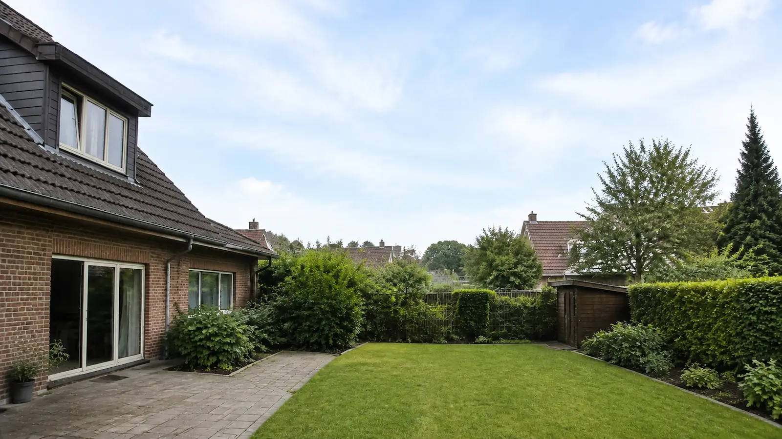 Derselbe Garten nach der Fällung: freie Rasenfläche, kein Stubben, Pflaster und Beete unbeschädigt